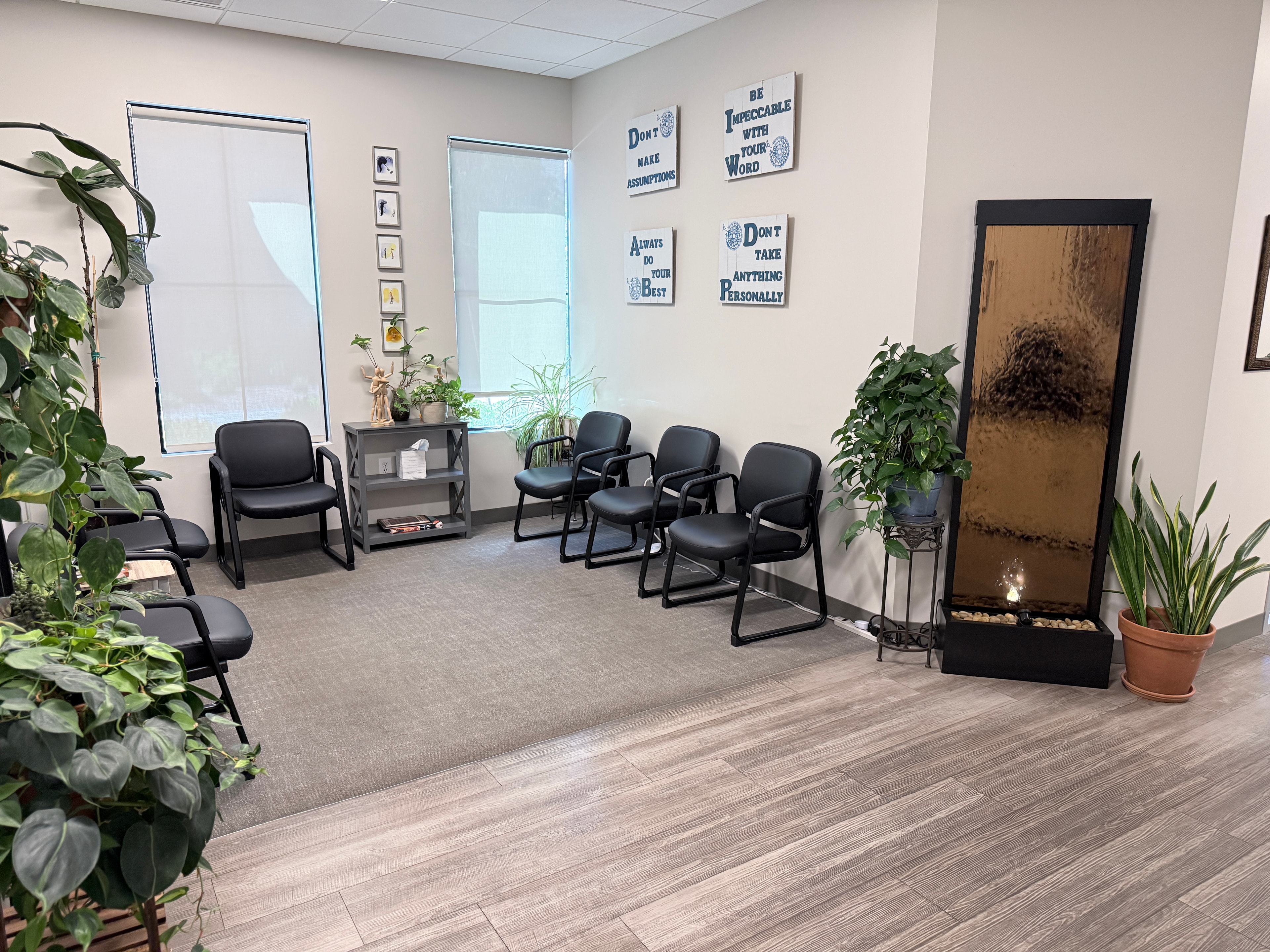 Welcoming waiting room with plants, motivational signage, and a water feature